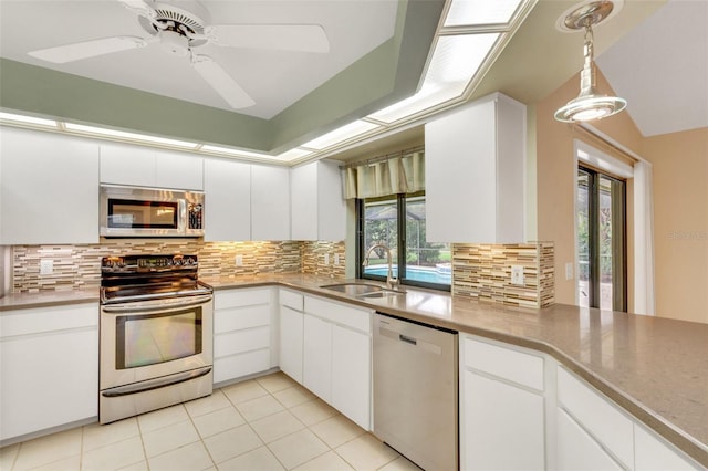 kitchen with stainless steel appliances, white cabinets, a sink, and tasteful backsplash