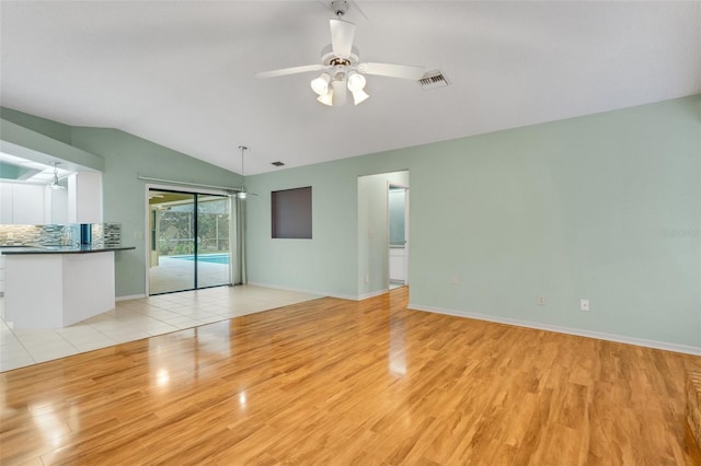 spare room featuring a ceiling fan, baseboards, vaulted ceiling, visible vents, and light wood-style floors