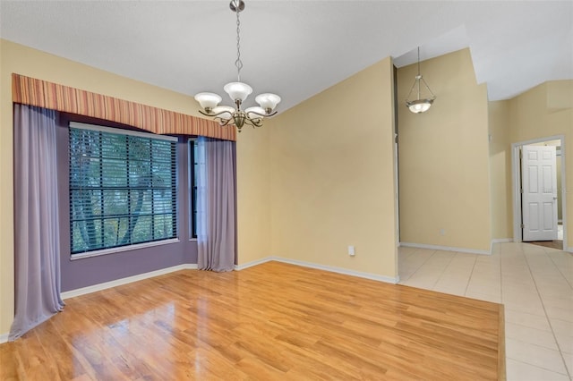 empty room featuring light wood finished floors, baseboards, vaulted ceiling, and a notable chandelier