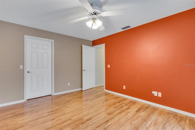 unfurnished bedroom featuring a ceiling fan, visible vents, light wood-style flooring, and baseboards