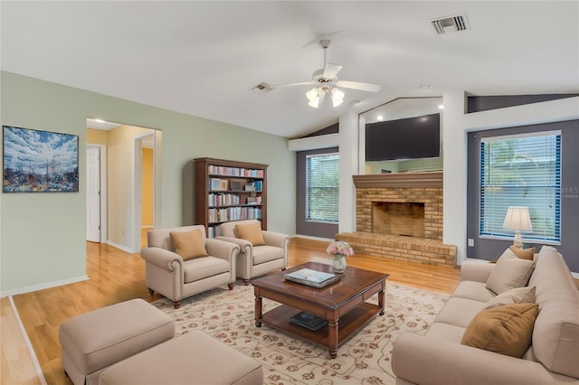 living area with light wood-type flooring, visible vents, and vaulted ceiling