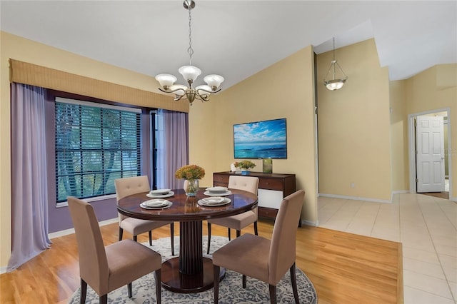 dining area featuring light wood finished floors, baseboards, a chandelier, and vaulted ceiling