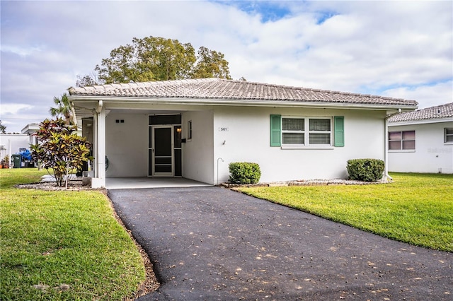 single story home featuring aphalt driveway, stucco siding, a tiled roof, and a front yard