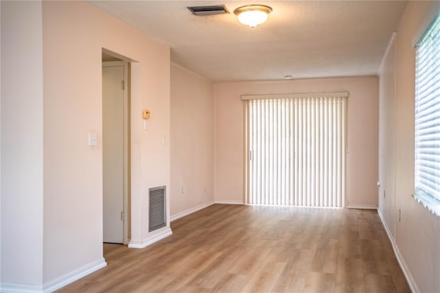 empty room with visible vents, baseboards, a textured ceiling, and wood finished floors