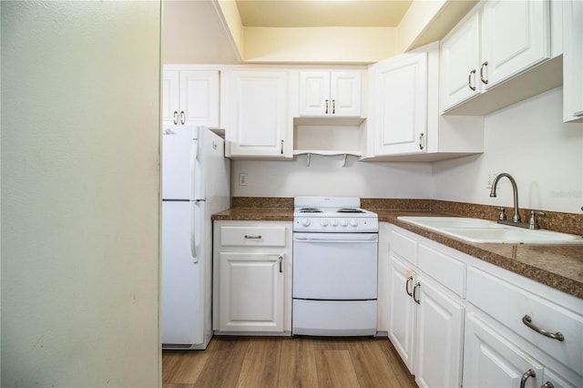 kitchen with white appliances, a sink, white cabinetry, dark countertops, and light wood-type flooring