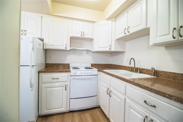 kitchen with a sink, dark countertops, white cabinetry, white appliances, and light wood-style floors