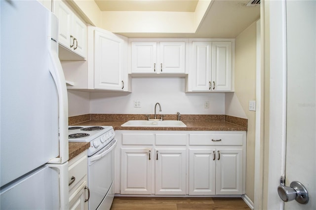 kitchen featuring white cabinetry, white appliances, dark countertops, and a sink