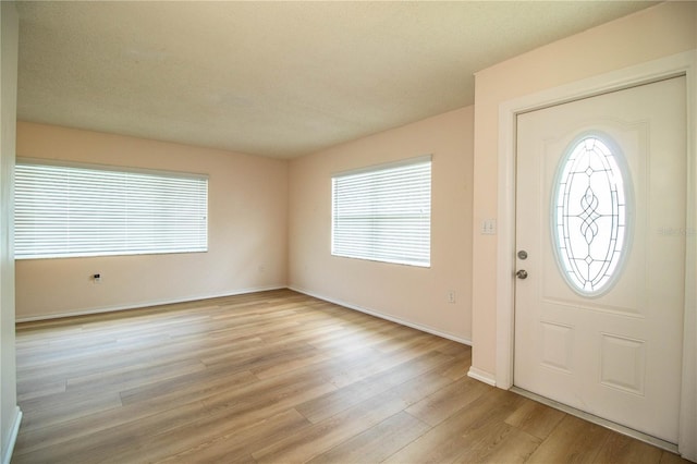 foyer with baseboards and light wood-style floors