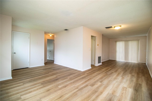 empty room with visible vents, light wood finished floors, and a textured ceiling