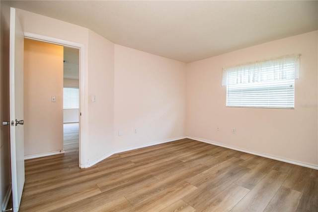 spare room featuring baseboards and light wood finished floors