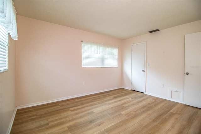 empty room featuring visible vents, baseboards, and light wood-style flooring