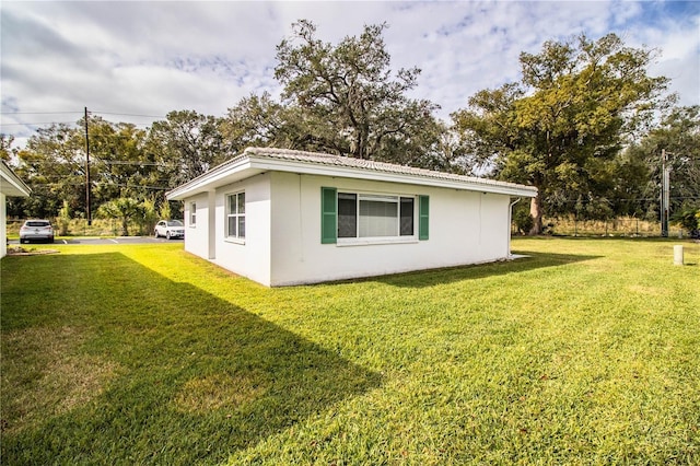 view of side of home featuring metal roof and a yard