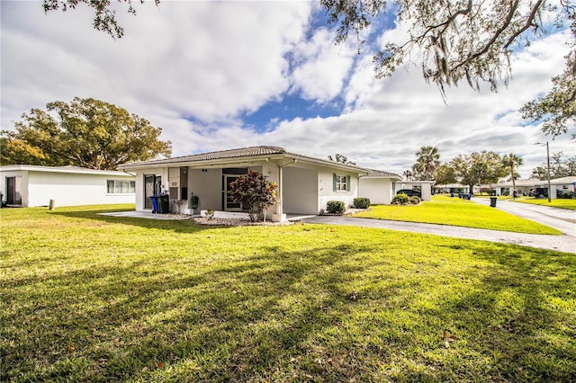 ranch-style house with aphalt driveway, stucco siding, and a front lawn