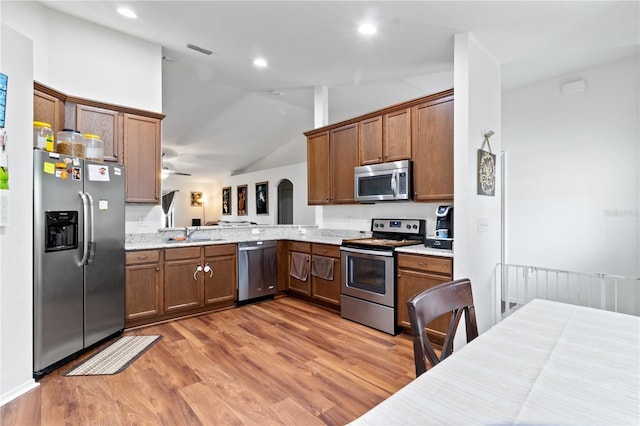 kitchen with light wood-type flooring, stainless steel appliances, vaulted ceiling, ceiling fan, and sink