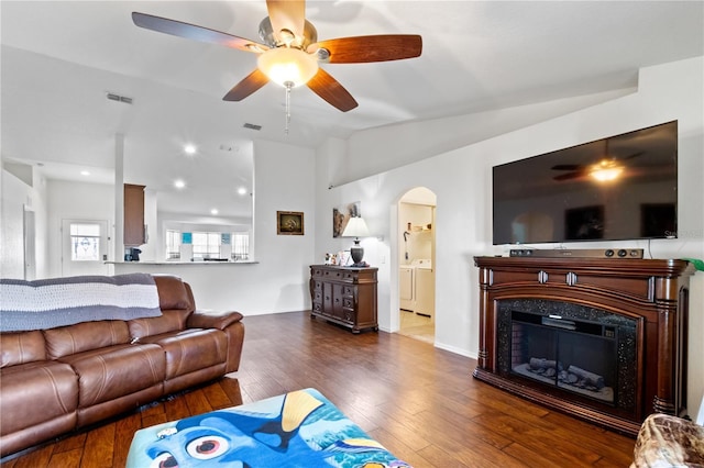 living room featuring washer and dryer, a high end fireplace, dark wood-type flooring, and vaulted ceiling