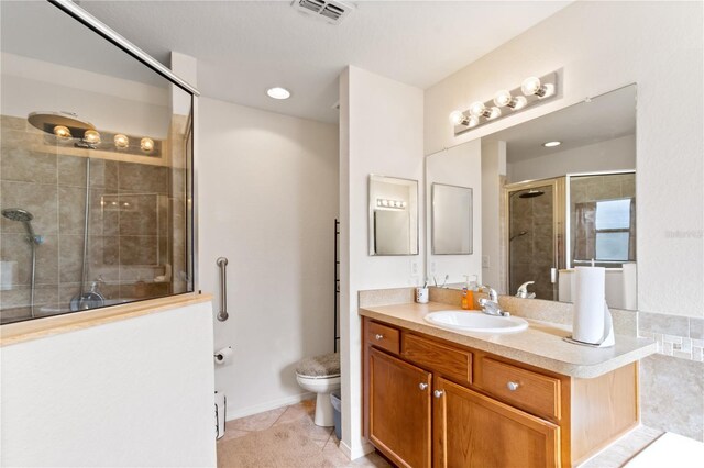 bathroom featuring tile patterned flooring, vanity, toilet, and a shower with shower door