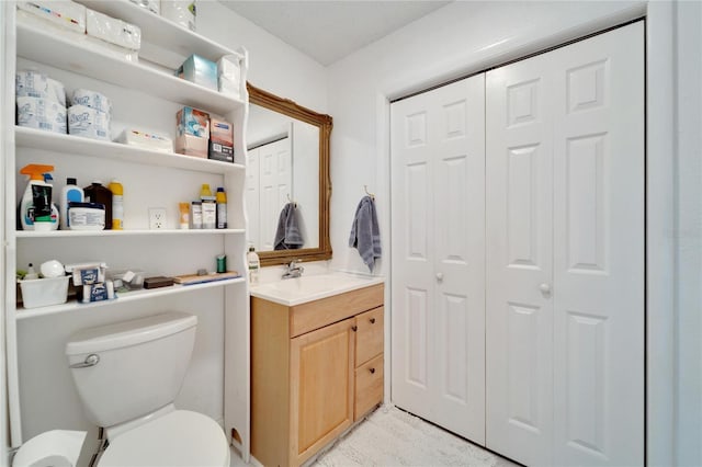 bathroom featuring toilet, a closet, and vanity