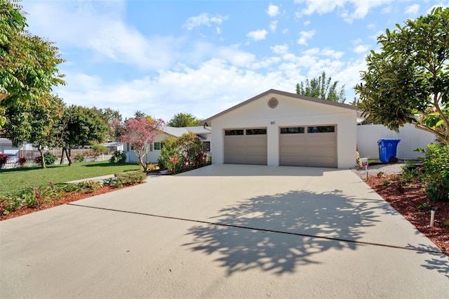 ranch-style house featuring driveway, an attached garage, fence, a front yard, and stucco siding