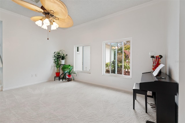 sitting room with baseboards, a ceiling fan, crown molding, and carpet flooring