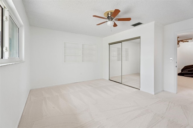 unfurnished bedroom featuring carpet floors, a closet, visible vents, and a textured ceiling