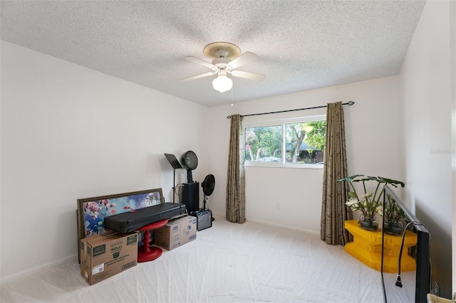 interior space featuring carpet, baseboards, ceiling fan, and a textured ceiling