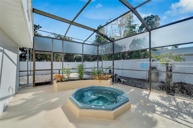 view of pool with glass enclosure, a patio area, a fenced backyard, and an outdoor hot tub