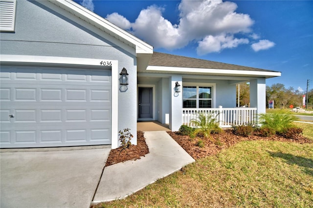 entrance to property with a garage, a yard, and covered porch