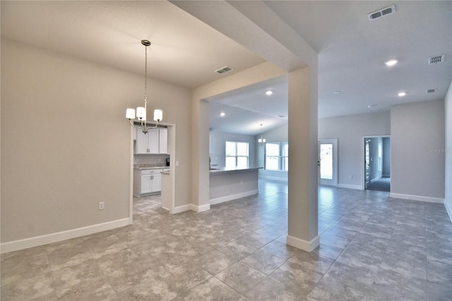 unfurnished living room with a notable chandelier and vaulted ceiling