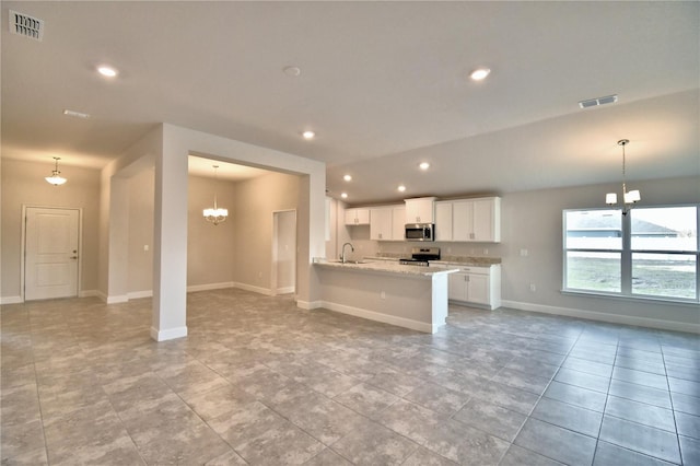 kitchen with appliances with stainless steel finishes, pendant lighting, white cabinets, a notable chandelier, and light stone counters