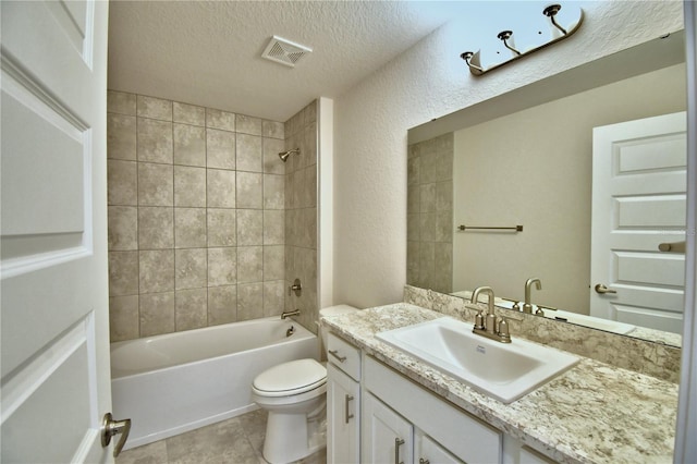 full bathroom with tiled shower / bath, tile patterned flooring, vanity, toilet, and a textured ceiling