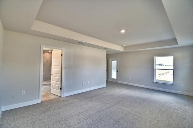 carpeted empty room featuring a raised ceiling