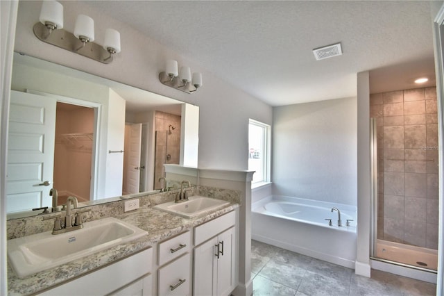 bathroom with vanity, tile patterned floors, plus walk in shower, and a textured ceiling