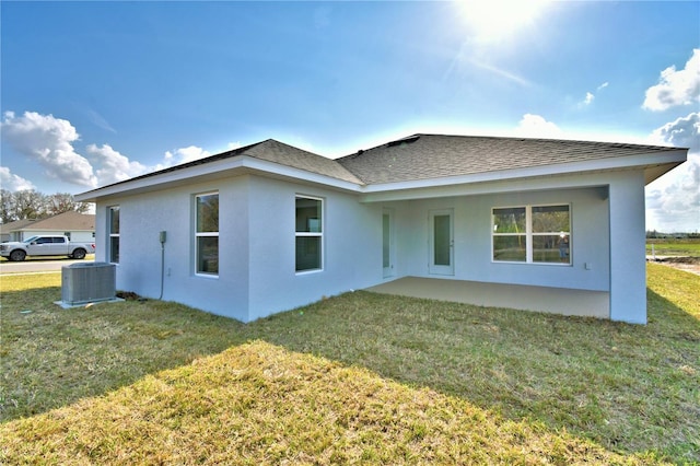 rear view of property with a patio, a yard, and central AC