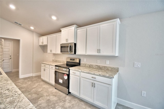 kitchen featuring stainless steel appliances, light stone countertops, vaulted ceiling, and white cabinets