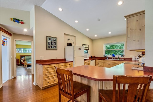 kitchen with vaulted ceiling, sink, white appliances, and light wood-type flooring