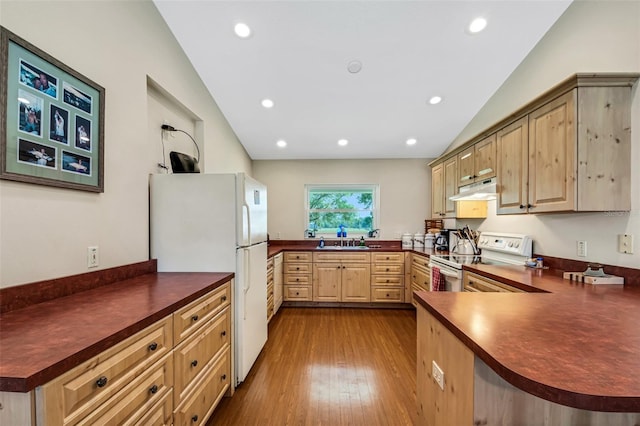 kitchen with lofted ceiling, white appliances, kitchen peninsula, and light wood-type flooring