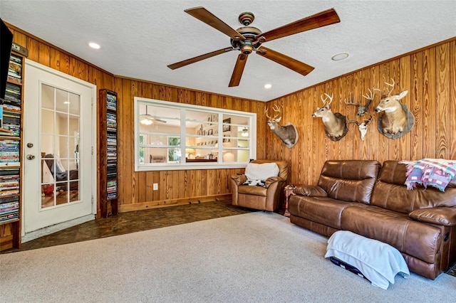 living room with dark colored carpet, a textured ceiling, and wooden walls