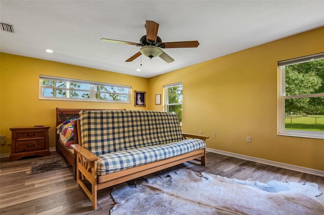 bedroom featuring wood-type flooring, a textured ceiling, multiple windows, and ceiling fan