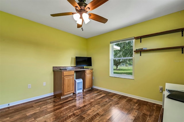 unfurnished office with ceiling fan and dark wood-type flooring