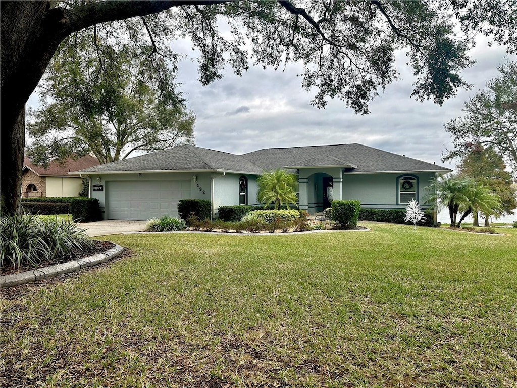 ranch-style home featuring a garage and a front lawn