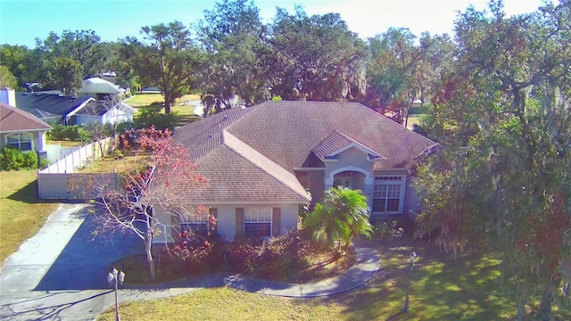 view of front of home with roof with shingles, fence, a front lawn, and stucco siding