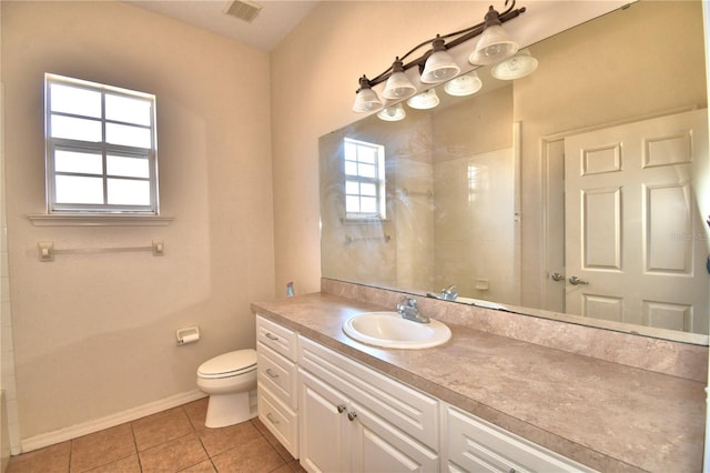 bathroom featuring toilet, tiled shower, tile patterned floors, and a wealth of natural light