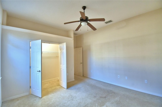 unfurnished bedroom with ceiling fan, light colored carpet, a spacious closet, and a closet