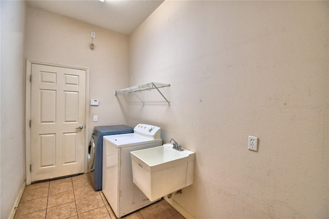 washroom featuring washer and clothes dryer, sink, and light tile patterned floors