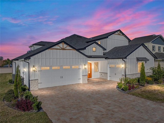 2728 Sunrise Landing Ln, Lakeland, FL 33812 - modern farmhouse style home featuring an attached garage, a shingled roof, stone siding, decorative driveway, and board and batten siding