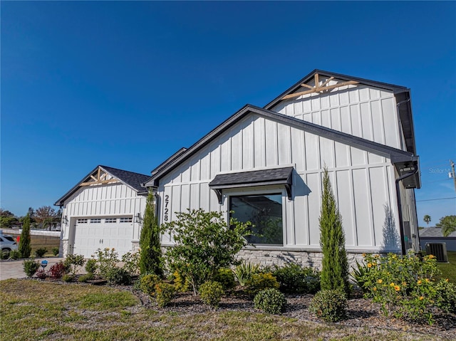 2728 Sunrise Landing Ln, Lakeland, FL 33812 - view of property exterior featuring board and batten siding, a garage, a shingled roof, and central AC unit