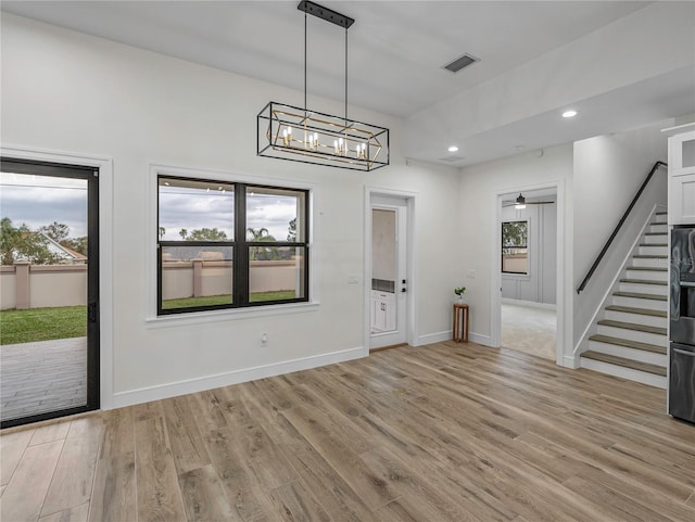 2728 Sunrise Landing Ln, Lakeland, FL 33812 - unfurnished dining area featuring stairway, light wood finished floors, recessed lighting, baseboards, and a chandelier