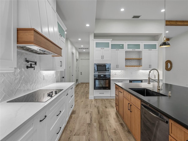 2728 Sunrise Landing Ln, Lakeland, FL 33812 - kitchen featuring black appliances, a sink, light wood finished floors, glass insert cabinets, and decorative backsplash