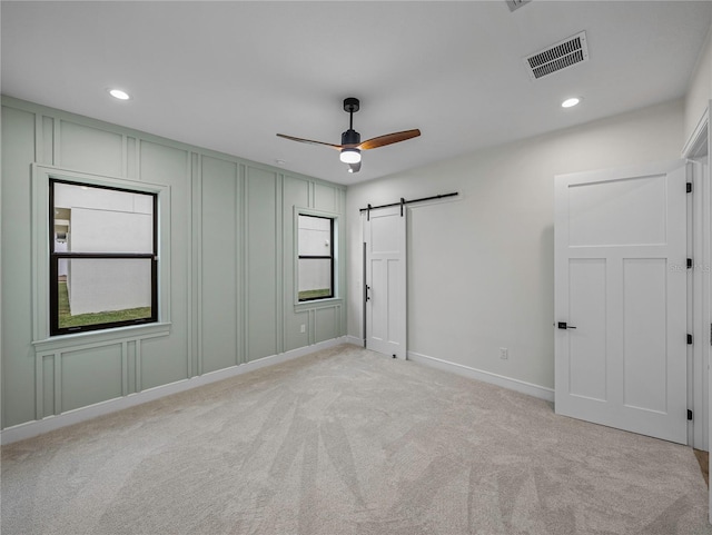 2728 Sunrise Landing Ln, Lakeland, FL 33812 - unfurnished bedroom featuring a barn door, a decorative wall, light carpet, recessed lighting, and baseboards