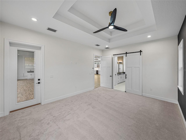 2728 Sunrise Landing Ln, Lakeland, FL 33812 - unfurnished bedroom with a barn door, a tray ceiling, baseboards, recessed lighting, and light carpet